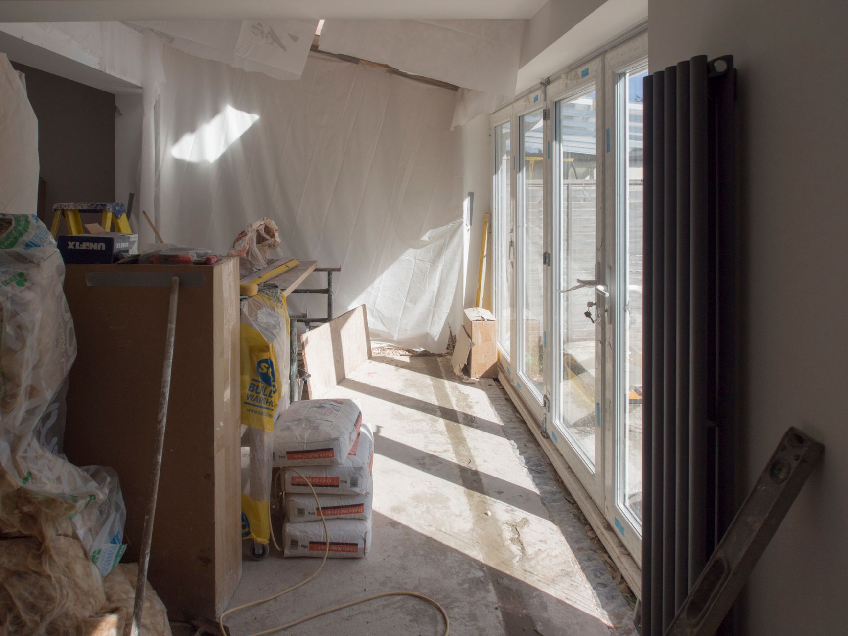 Lyst rum under renovering med nye glasdøre og byggematerialer